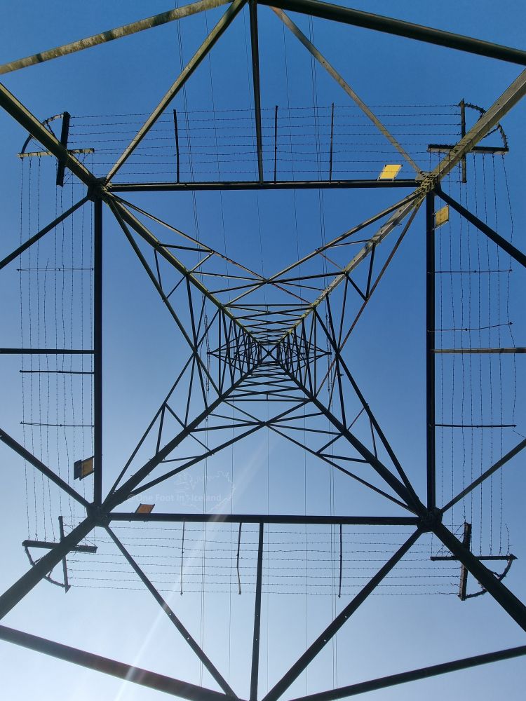 A view from underneath a pylon (or transmission tower, if you're that way inclined!) looking up to a clear blue sky. The picture is all squares and triangles, pretty symmetrical 
