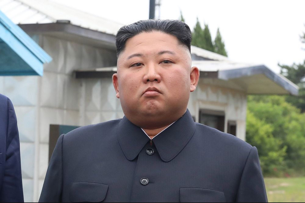 Kim Jong Un posing in a dark suit with a stern judgemental face. Hair is perfectly square and slicked back.