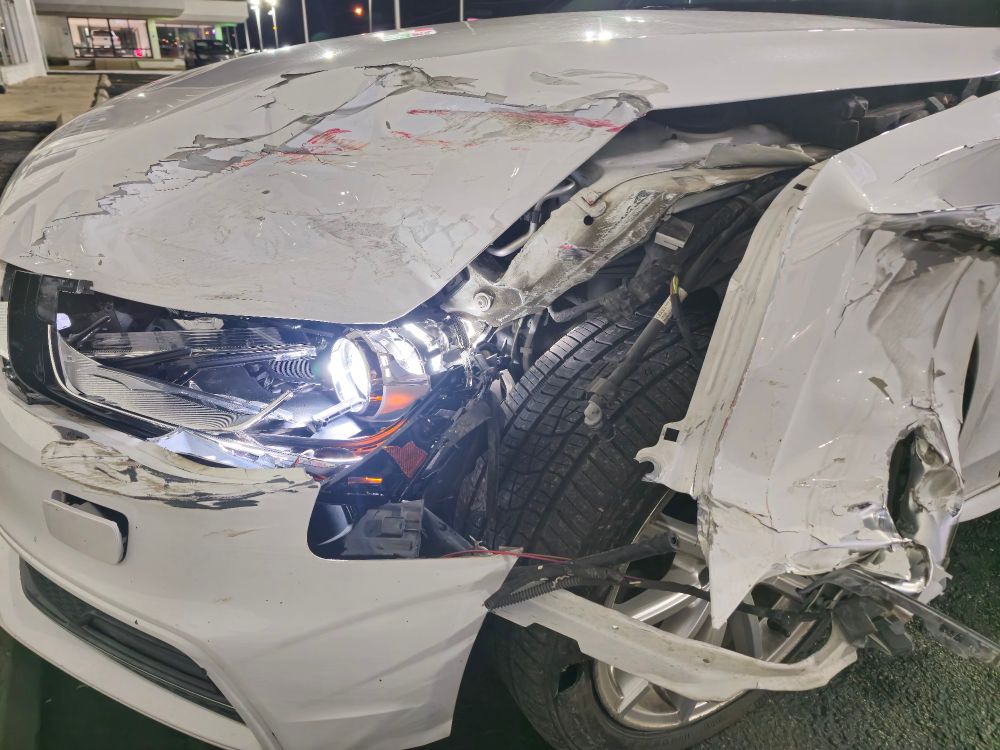 White audi a4 front driverside corner,
destroyed by crash exposing internal
components of the headlight, bumper, and
tire, slight red streak on hood from paint of
other vehicle.