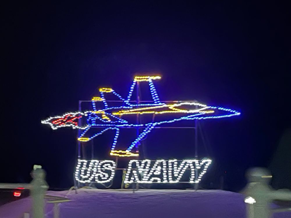 Drive through Holiday light display of a blue and yellow fighter jet with the words us navy underneath