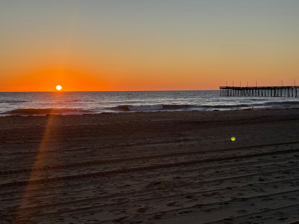 Sunrise on the beach - the sun is just over the horizon and the pier is visible to the right side of the photo