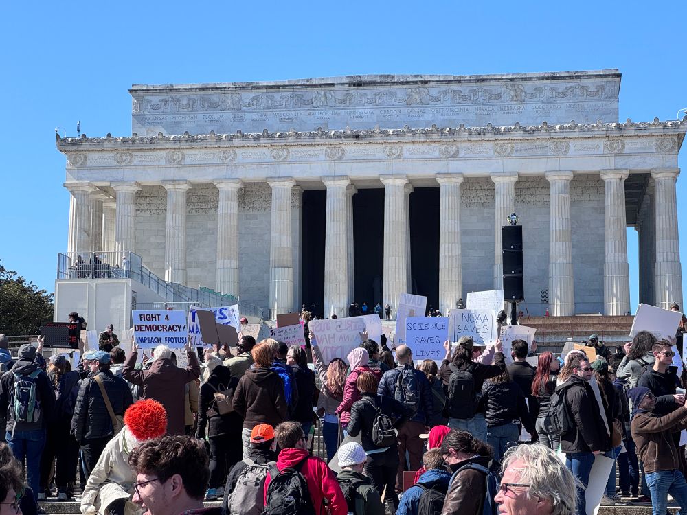 Crowd holding signs in front of Lincoln Memorial
