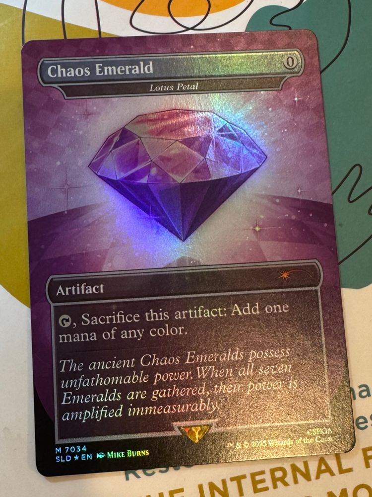 A foil #mtg card, “Chaos Emerald” #7034, which is a reskinned Lotus Petal, a 0 mana artifact that reads “Tap, Sacrifice this artifact: Add one mana of any color.

The ancient Chaos Emeralds possess unfathomable power. When all seven Emeralds are gathered, them power is amplified immeasurably.”