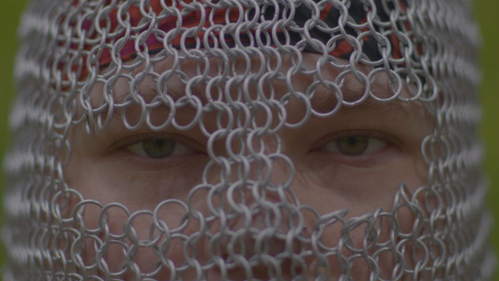 close up head shot of TOMMYXBEO wearing a chainmail headpiece with extreme shallow depth of field, with only his eyes in focus