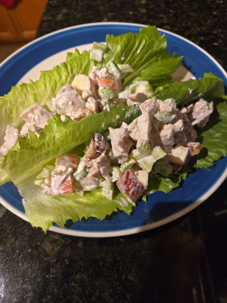 Plate with lettuce boats with chicken salad inside of it.