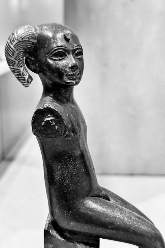 En bronze noir et or sur un socle moderne.
La mèche de l'enfant est incrustée d'or. Horus devait être assis sur les genoux de sa mère Iris, tourné vers son sein.