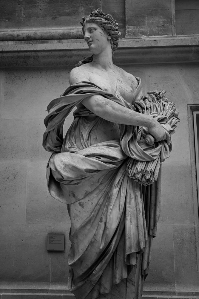 Statue de l'Été représenté sous les traits d'une femme qui porte dans son bras gauche une gerbe de blé que sa main droite vient recouvrir. 
