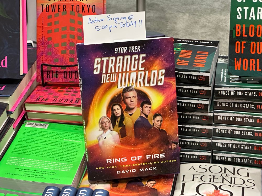 A copy of SNW: RING OF FIRE atop a stack of other books in booth 3409, for my 5PM signing.