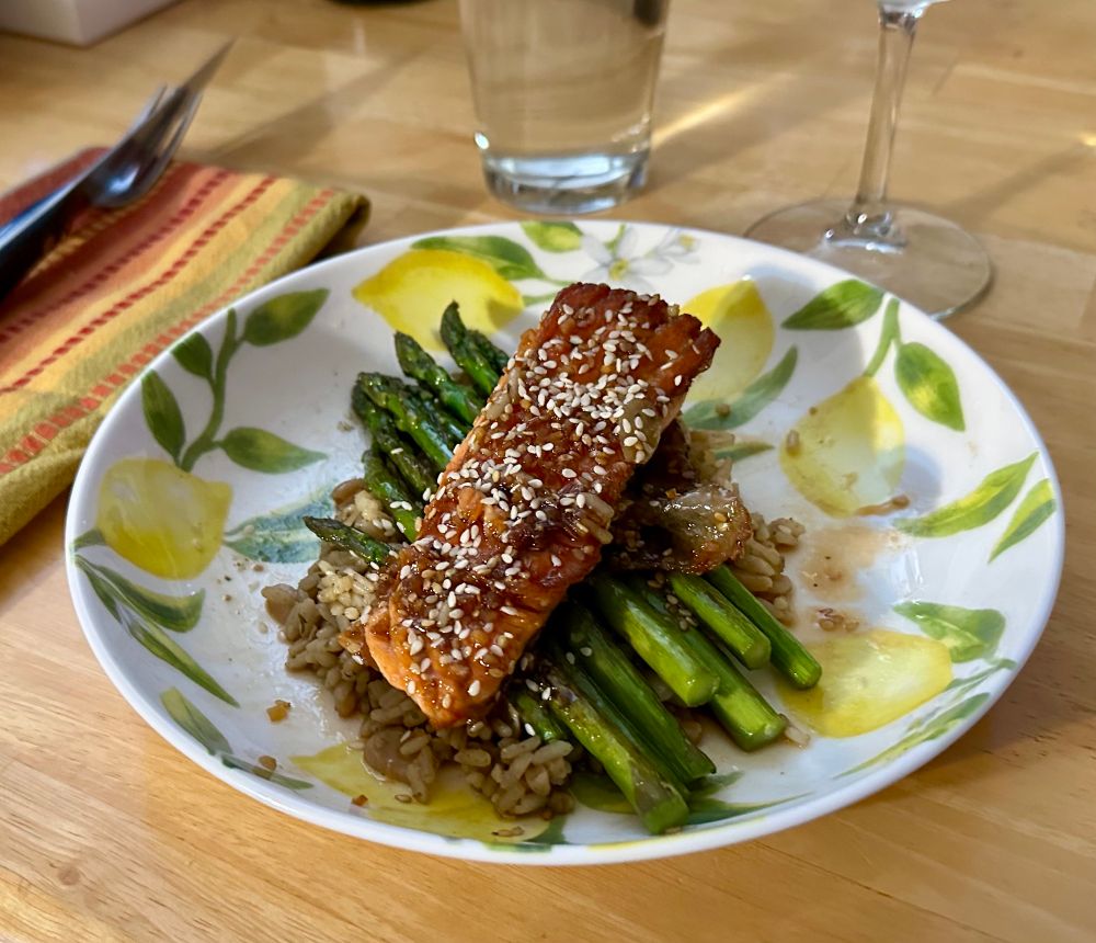 Teriyaki-glazed pan-seared wild salmon over seared asparagus finished with sesame oil atop a bed of wild herb rice pilaf with toasted slivered almonds.