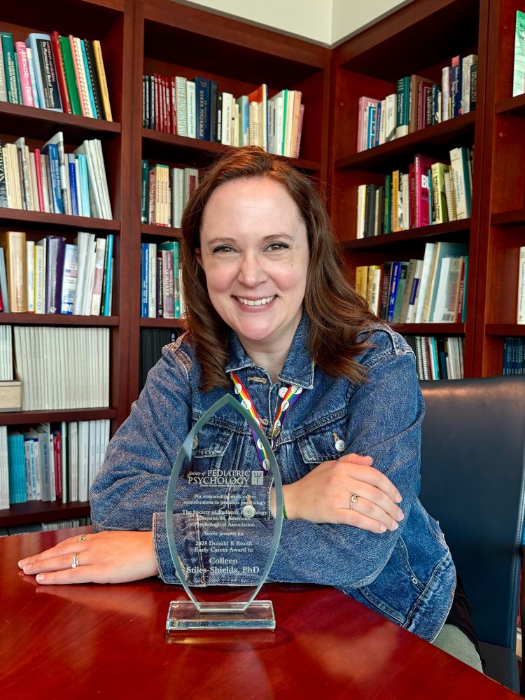 Colleen poses in a library with Early Career Award