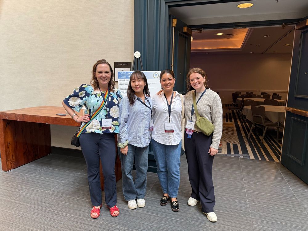Colleen, Danbi, Gabby, and Elyse pose in business casual clothes in front of a sign at SPPAC
