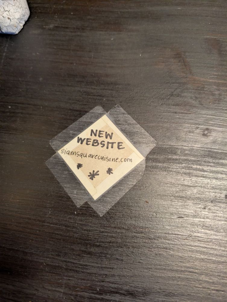 Close up of the tiny square of paper advertising that the restaurant has a new website 