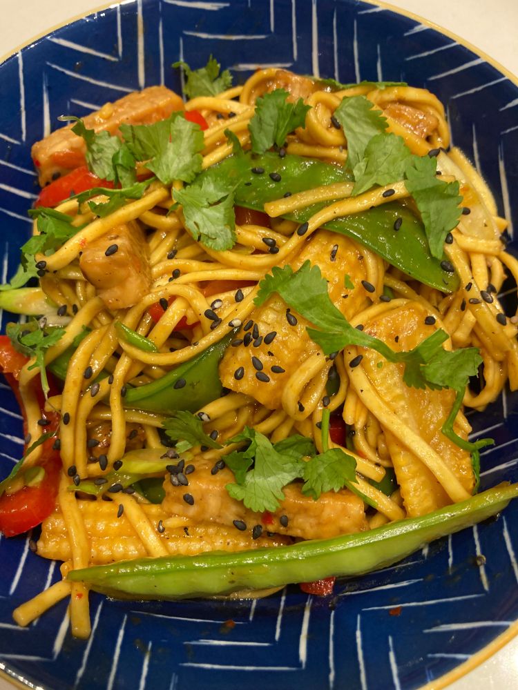 Stir fry of noodles, tempeh, mange tout, red pepper, spring onions and baby corn in a sweet chilli sauce with a sprinkle of black sesame seeds and coriander 