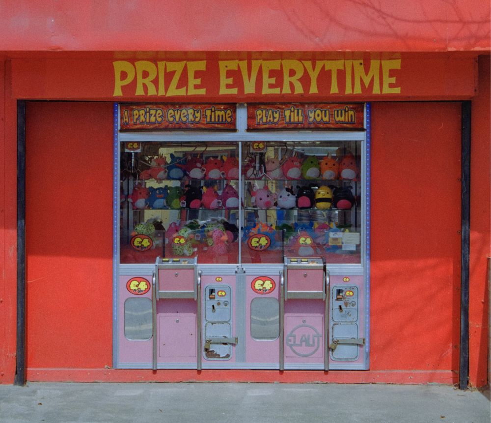 Two "A prize every time" machines set into a completely red building with "PRIZE EVERYTIME" in yellow above the machines. 