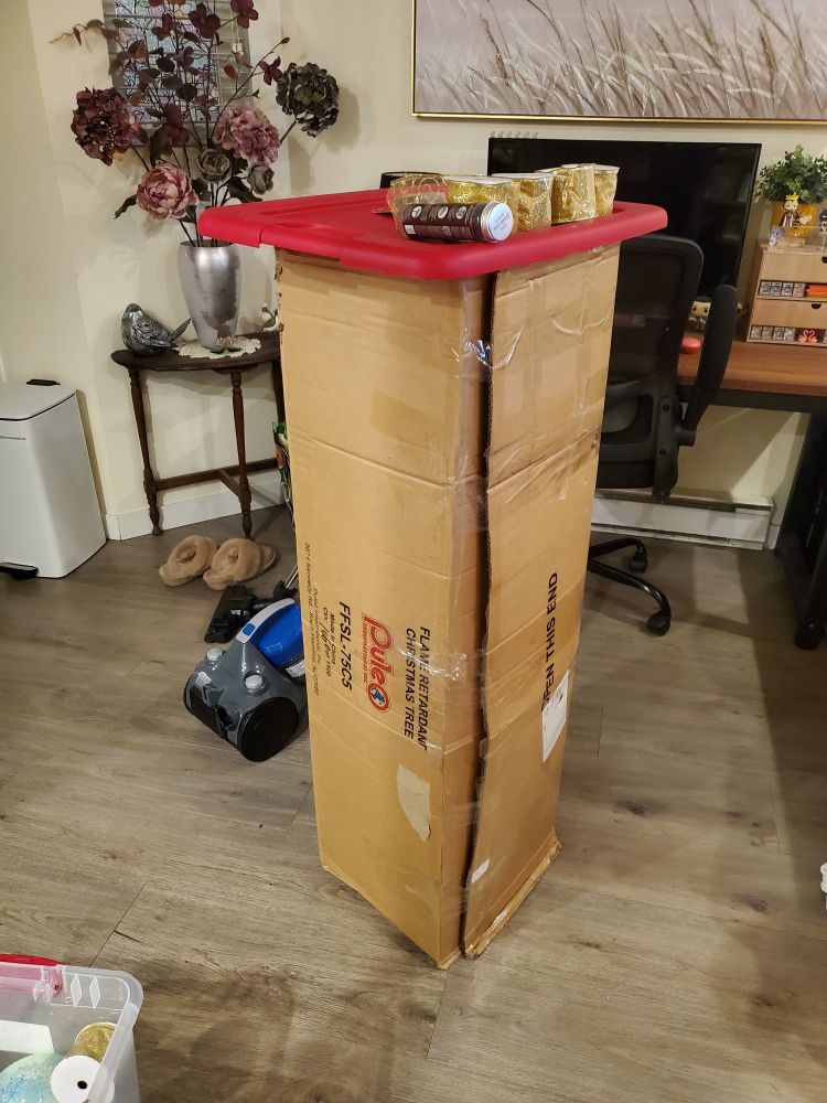 a boxed christmas tree, some packages of ribbon sitting on top of it. happy holidays, fuckers!