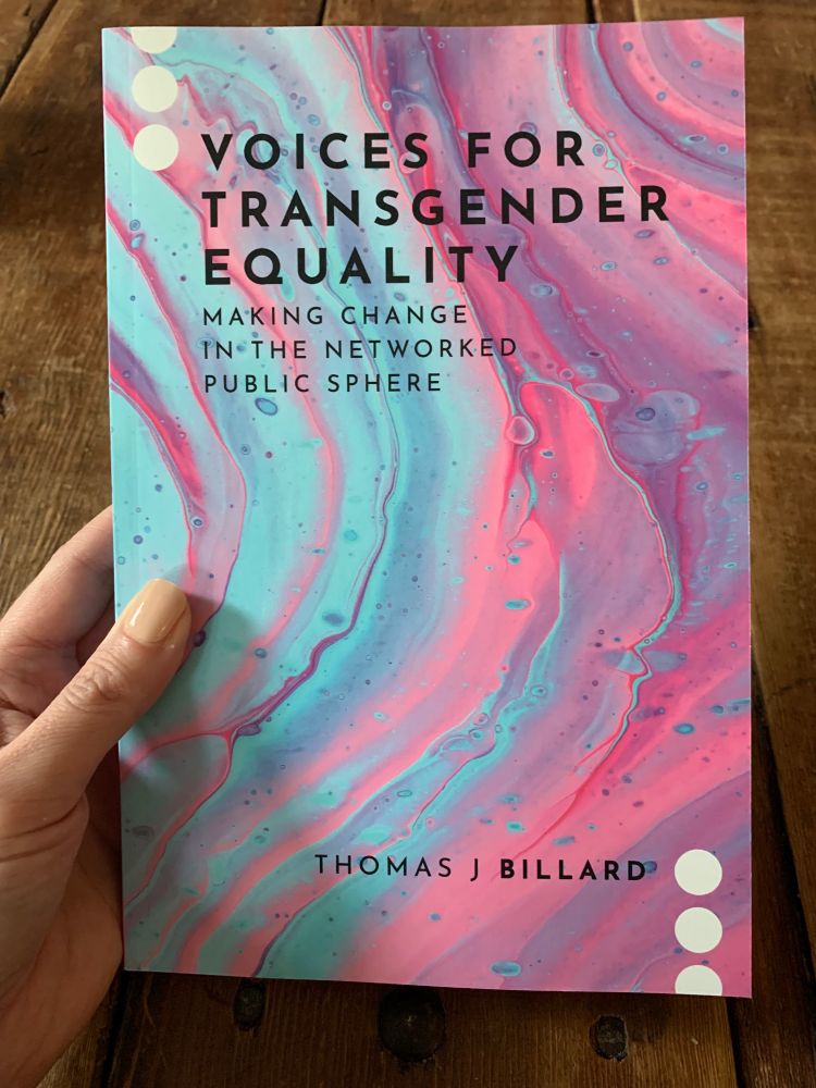 Photo of a hand holding the book Voices for Transgender Equality by Thomas J Bollard.
