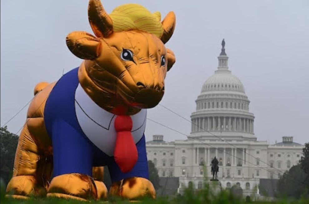 The Trump Golden Calf inflatable in front of the US Capital building. It's a golden calf with a blue suit and red tie and blond hair. It was created to remind people that Trump's policies are not in line with Jesus's teachings.