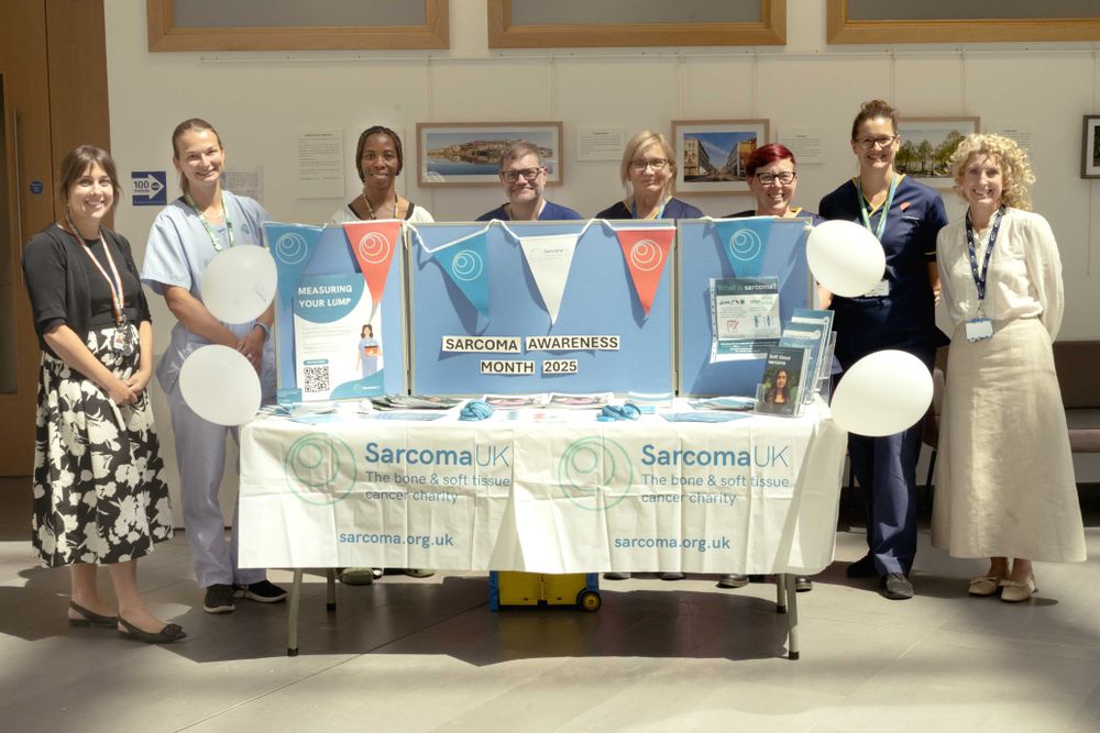 Photo of the Bristol team around a stand which displays information on sarcoma.