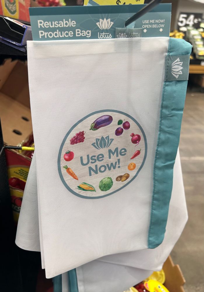 Reusable produce bag at the grocery store with pictures of vegetables that says “use me now!”