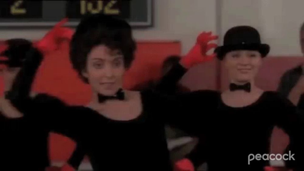 a group of women wearing black hats and red gloves are dancing together in a room .