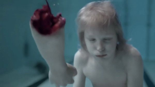 Un chaval buceando en una piscina y un brazo amputado. Fotograma correspondiente a la película ‘Déjame entrar’