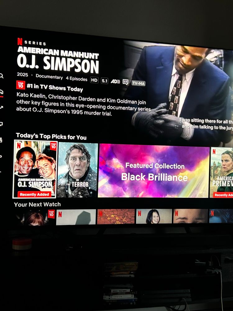 The Netflix homescreen touts a “Featured Collection: Black Brilliance” selection. Alongside “Terror” and “American Primeval” (neither of which have posters with black people) is the documentary “American Manhunt: O.J. Simpson”. The preview loaded on the TV shows him famously putting on a glove. And during Black History Month!