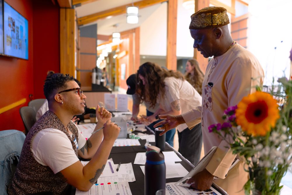 Cedarbrook Lodge, June 5, 2025 — An older gentleman speaks with a younger man at the registration table for the summit.