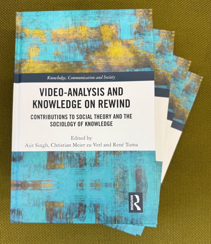 Four copies of the book Video-Analysis and Knowledge on Rewind displayed on green fabric. The cover shows a turquoise-yellow abstract design, with the title and editors (Ajit Singh, Christian Meier zu Verl & René Tuma) in black text. Routledge logo bottom right.