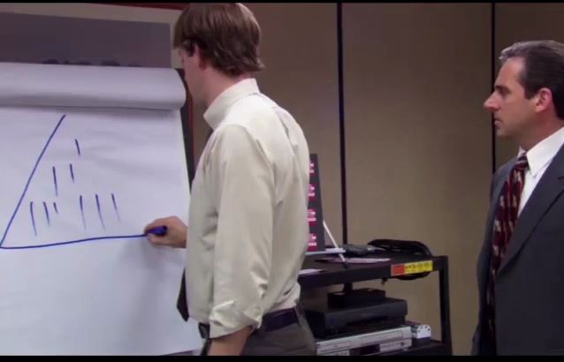 a man in a suit is standing next to another man drawing on a white board