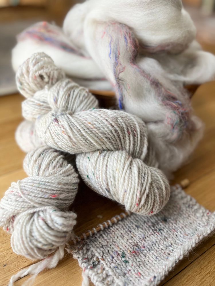 Tweedy white handspun yarn with flecks of red blue and brown. #handspinning 