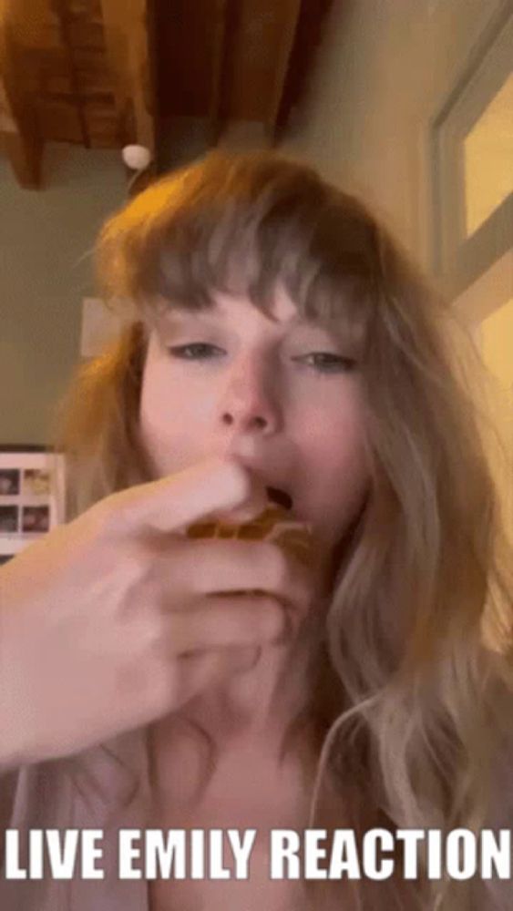 a woman is eating a sandwich with the caption " live emily reaction "