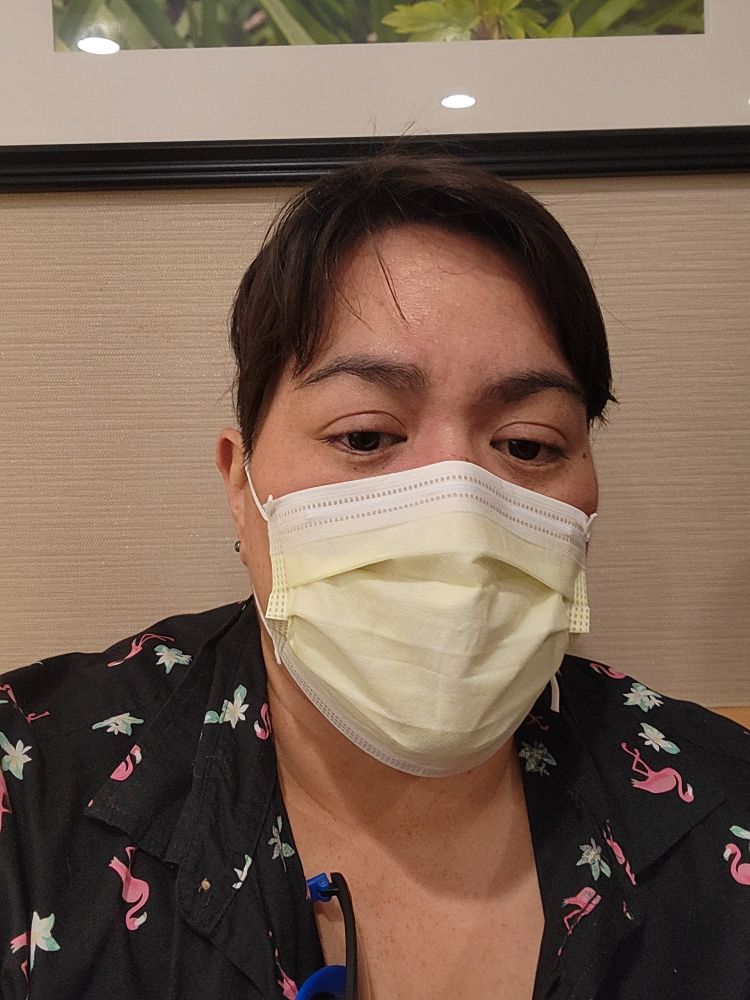 i am a tired person with brown hair and brown eyes wearing a yellow face mask and a black button down.