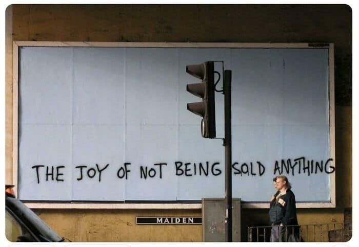 Graffiti on the wall that says "The Joy of Not Being Sold Anything"