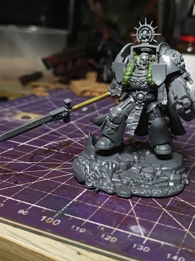 An unpainted space marine captain in terminator armor model that has been modified to become a space marine librarian.
The helm has been carved away to create a psychic hood, bulging green stuff has been used to create wires, and his sword has been extended with brass rod to become a halberd.