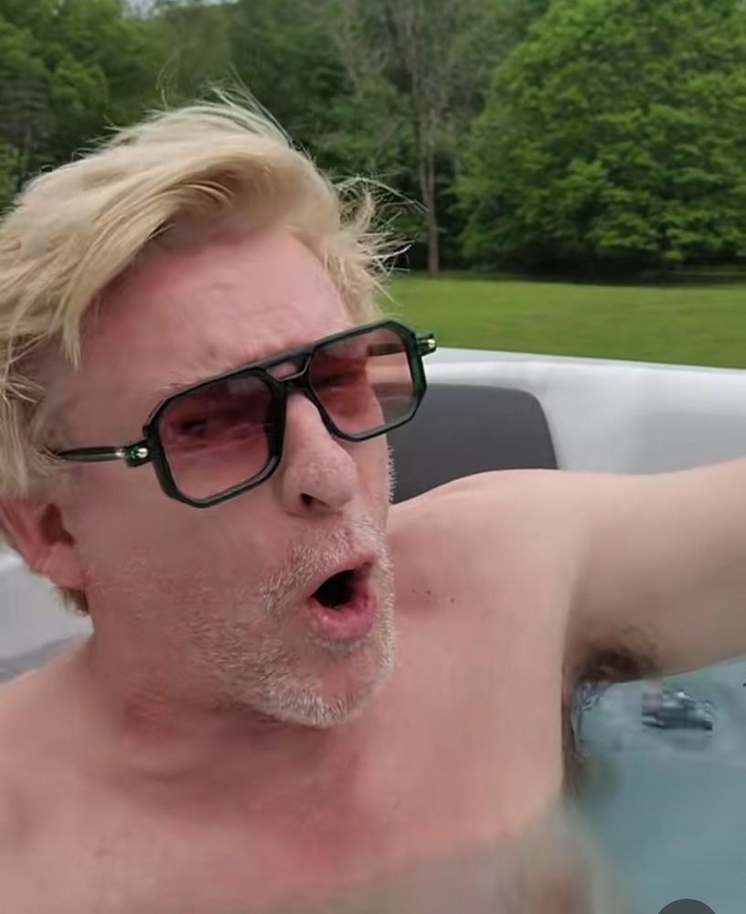 Rhys Darby sitting in a hot tub shirtless, with sunglasses on, mouth open and brow furrowed like he has a fucking point to make about something, arm still outstretched and providing an even better view of Armpit. i'm just glad to be here 