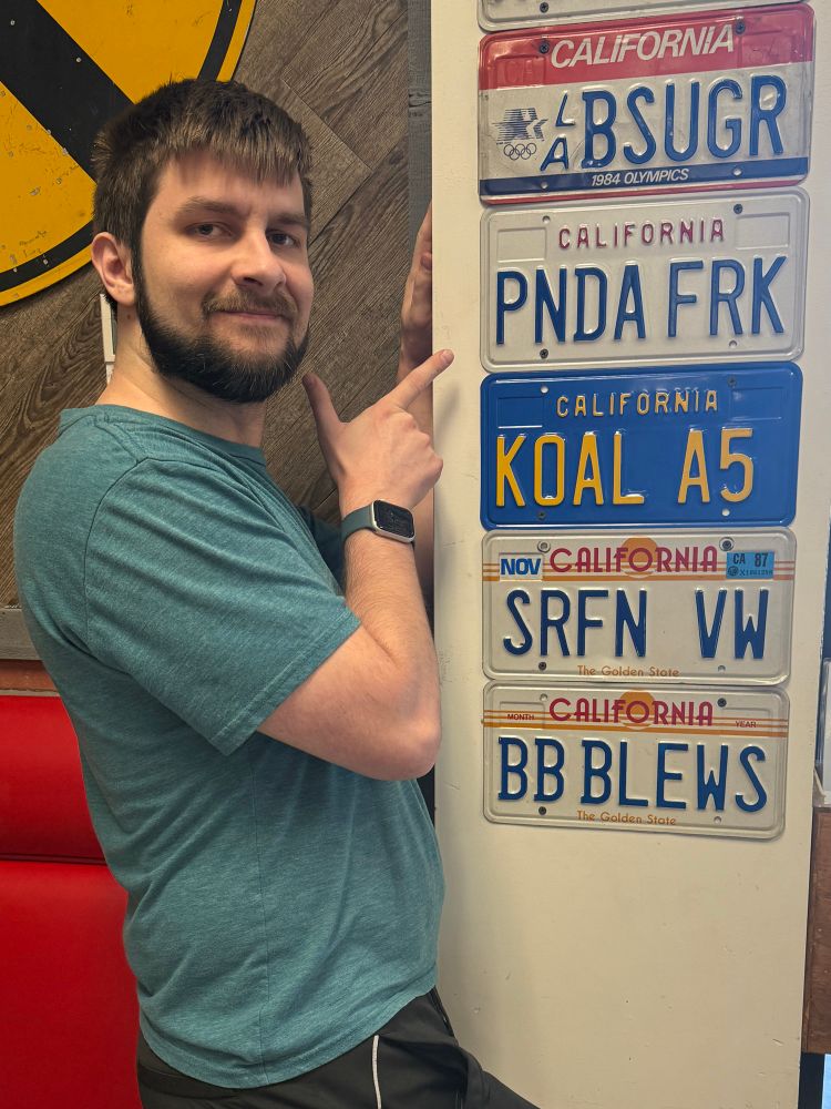 Dirk pointing at a California license plate with the letters “PNDA FRK”. appears to be an abbreviated version of “Panda Freak”.