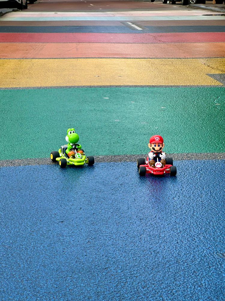 A rainbow coloured street crossing with Mario and Yoshi racing on go karts 