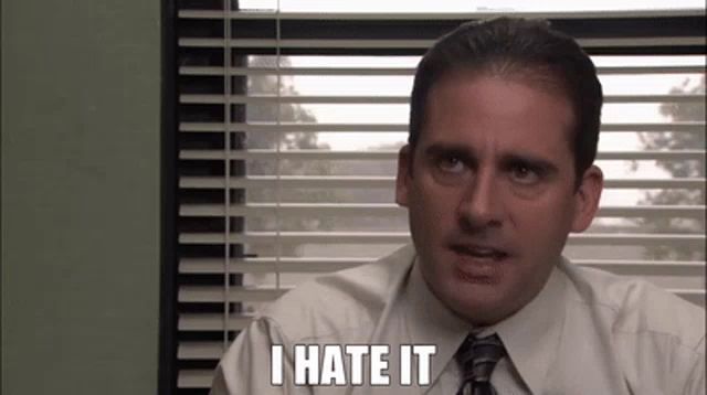 a man in a suit and tie is sitting in front of a window with blinds and says `` i hate it '' .
