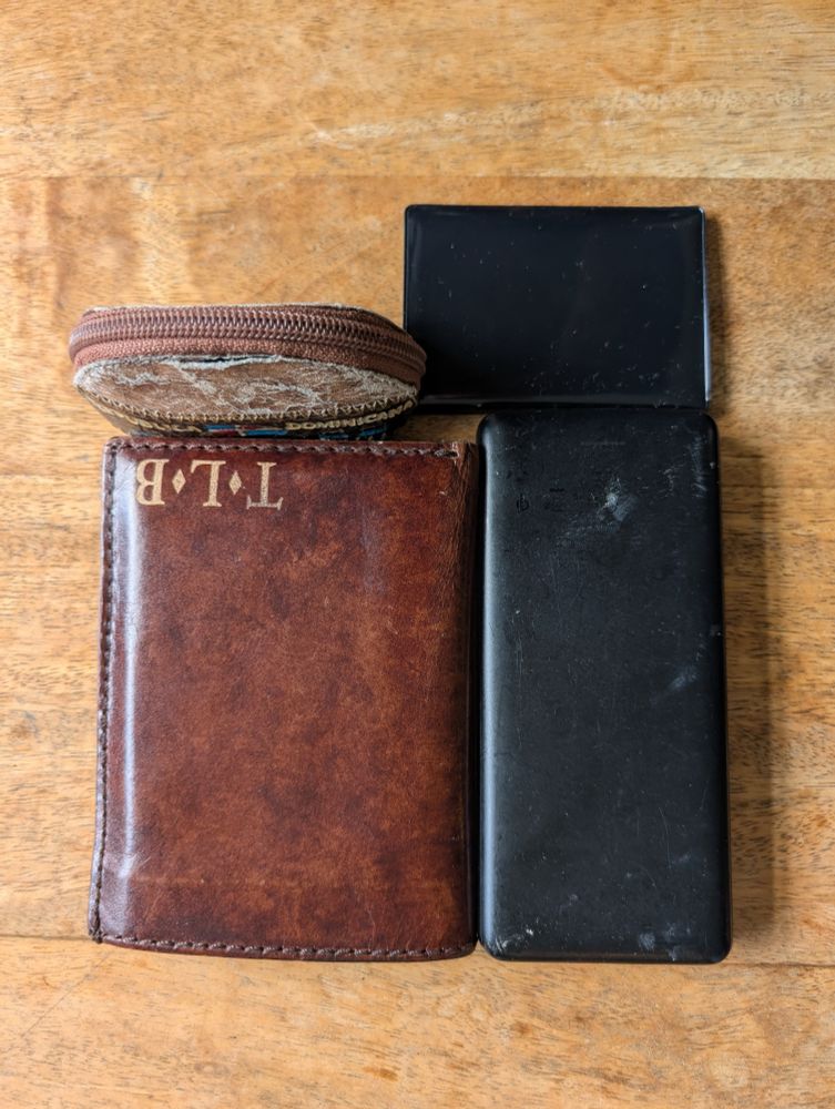 Change purse, wallet, passport wallet, and a battery on a table