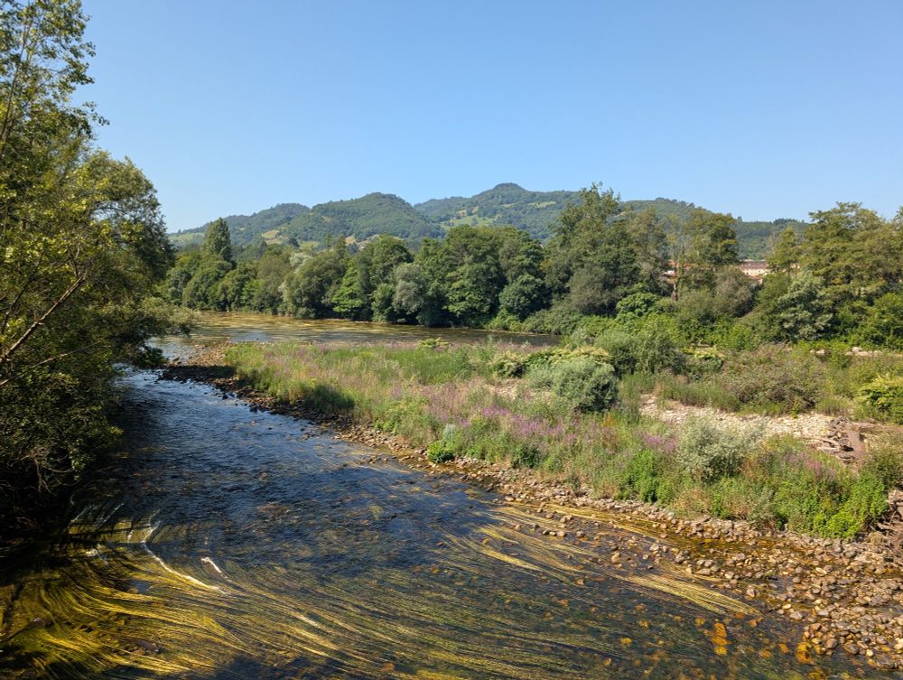 A river in the foreground with rolling hills in the background