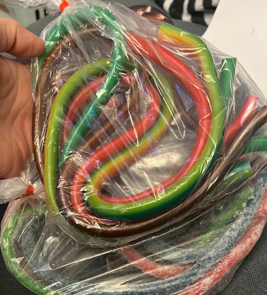 Zwei Tüten mit je 4 großen bunten Gummischnüren. Ich tippe jede ist ca 1m lang. Im Hintergrund sieht man eine Hand.