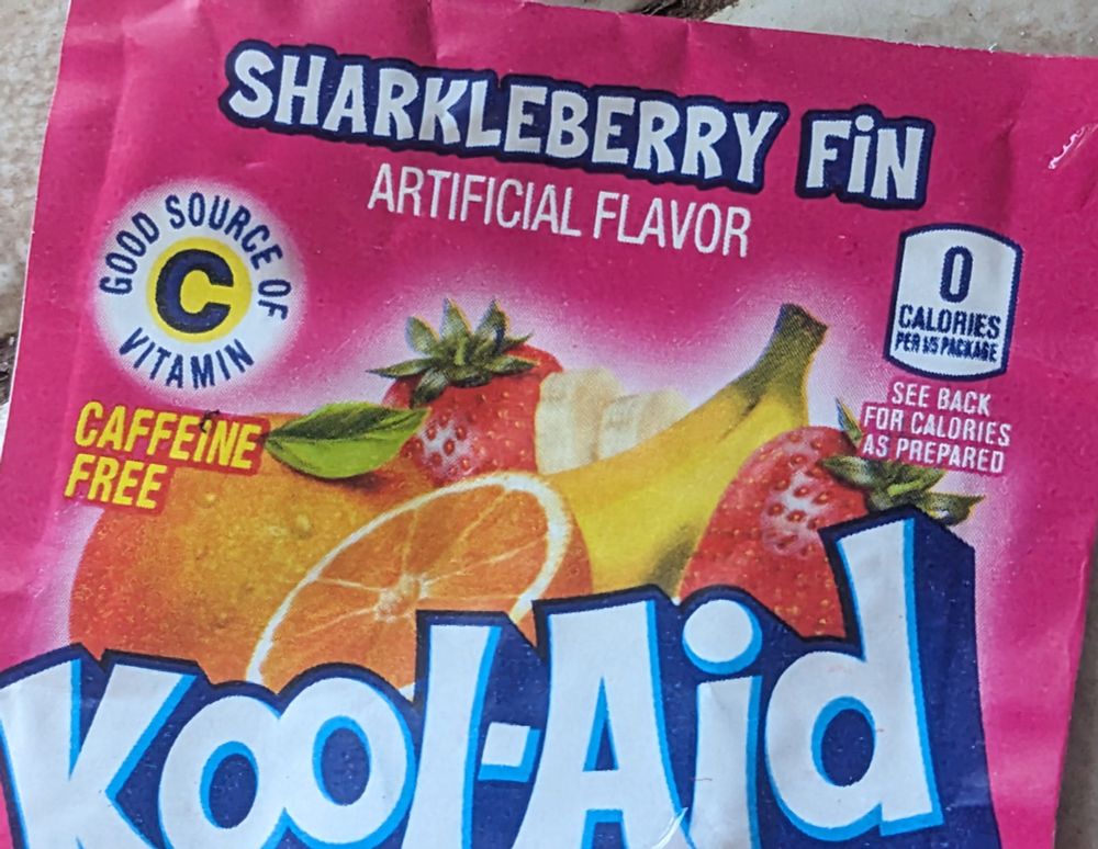 A Kool-Aid packet labeled SHARKLEBERRY FiN ARTIFICIAL FLAVOR 