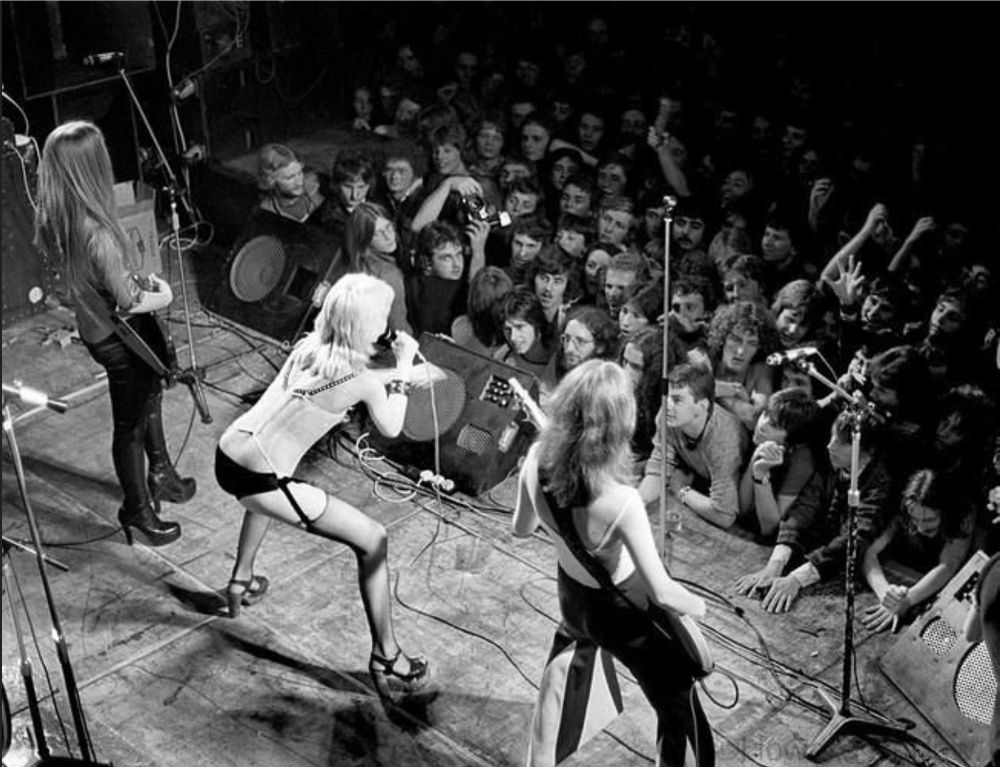 Overhead shot of the Runaways. L-R: Lita Ford, Cherie Currie, Jackie Fox. Joan Jett is off camera right.