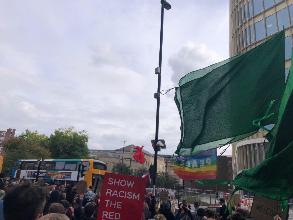 Rainbow Peace Flag, “Show Racism The Red Card” poster and green flags flying in Newcastle as part of the counter-protest to a far-right march.