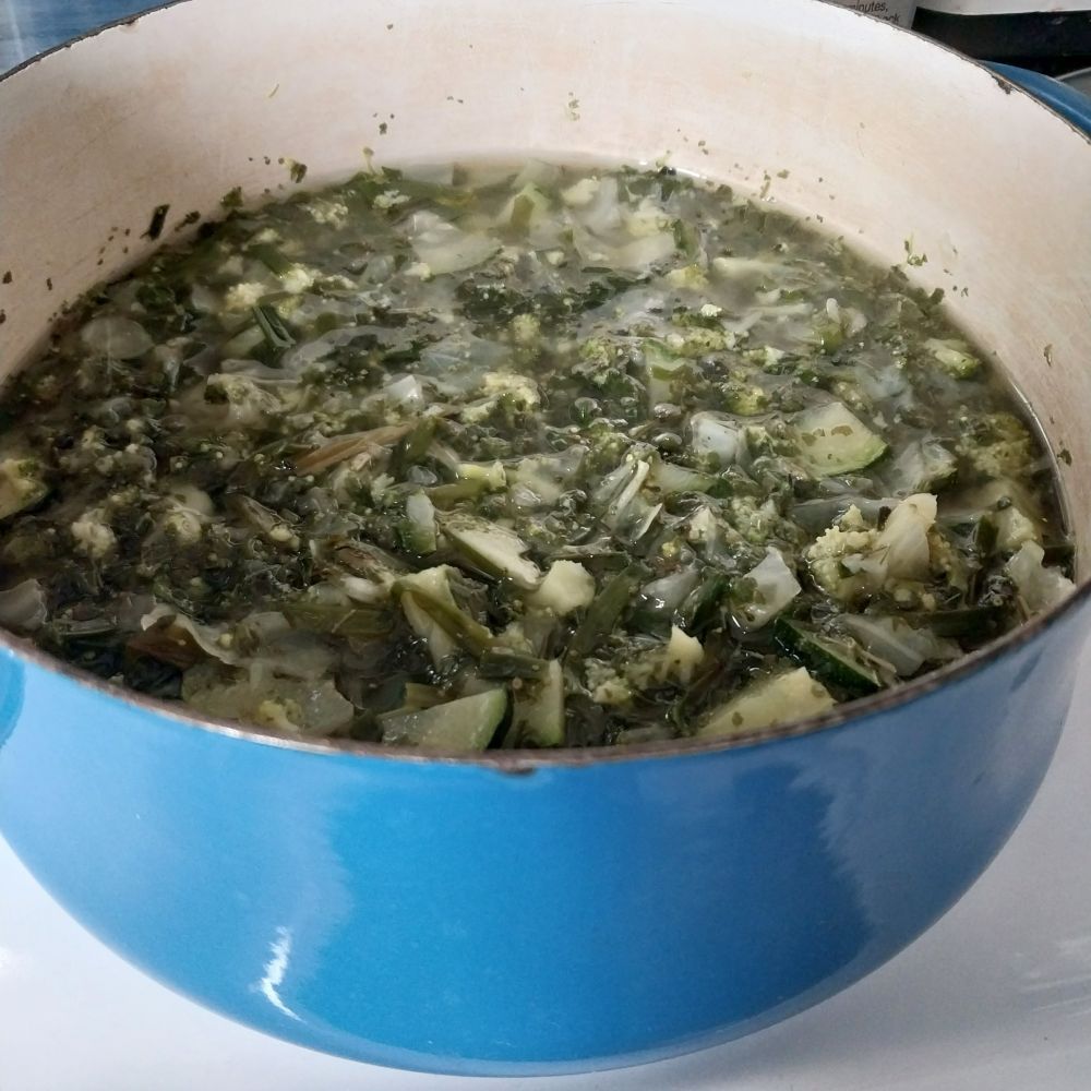 a blue enamel pot full of green vegetable soup.