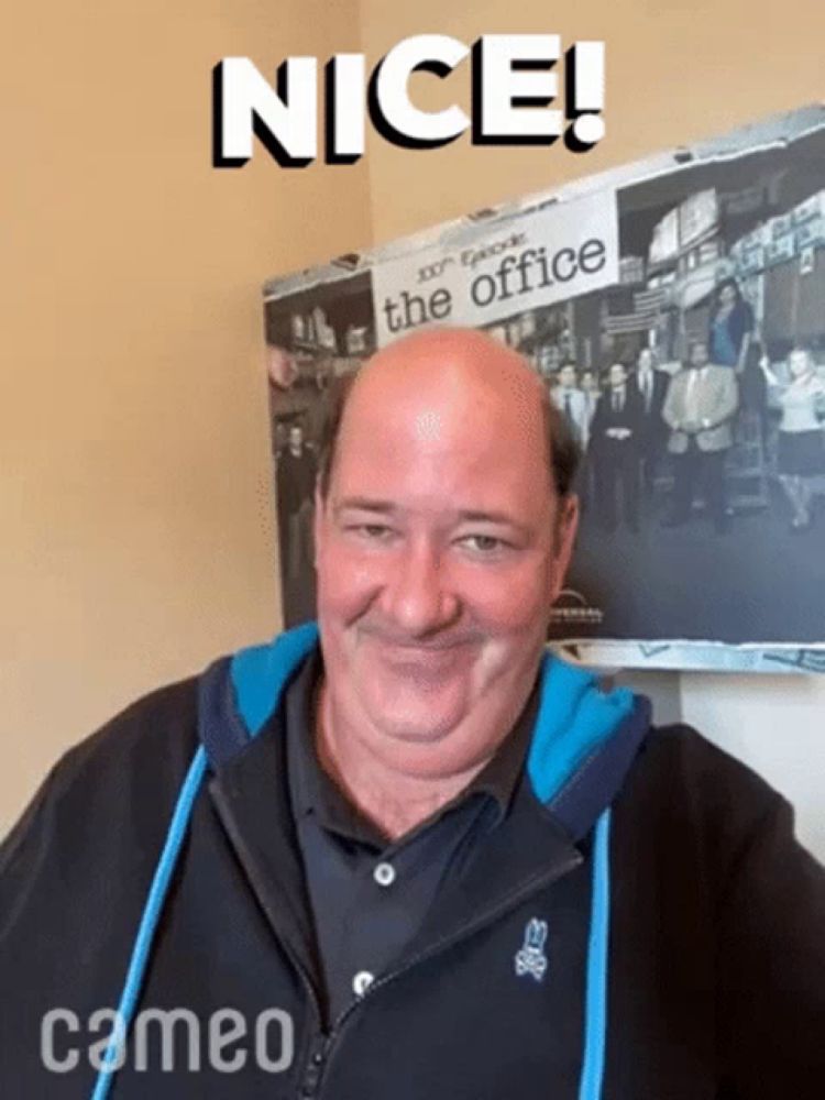 a bald man is smiling in front of a poster of the office