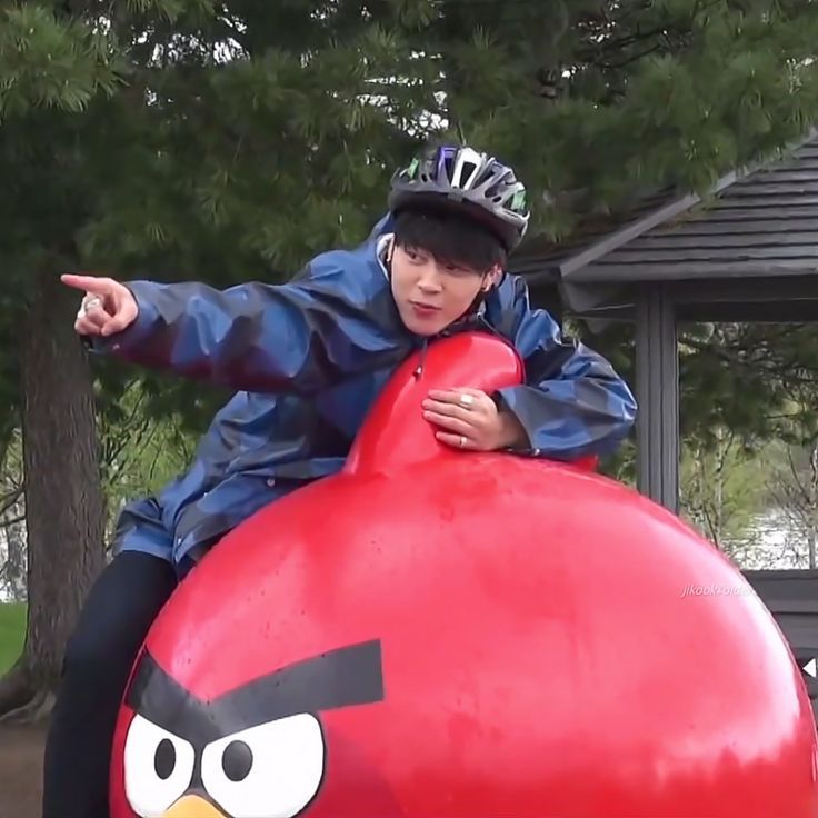 Jimin of BTS on top of a large, red Angry Birds figure. 