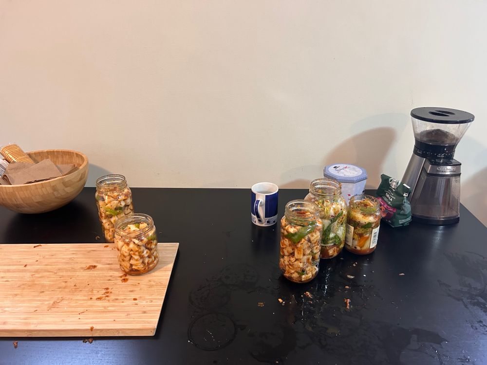 Jars of mixed kimchi in the middle of being filled with water