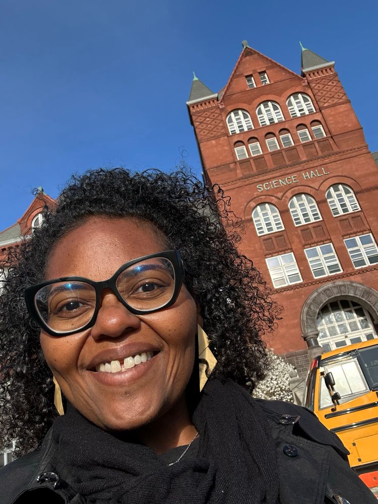 A woman smiling at the camera in front of a building that says Science Hall. 