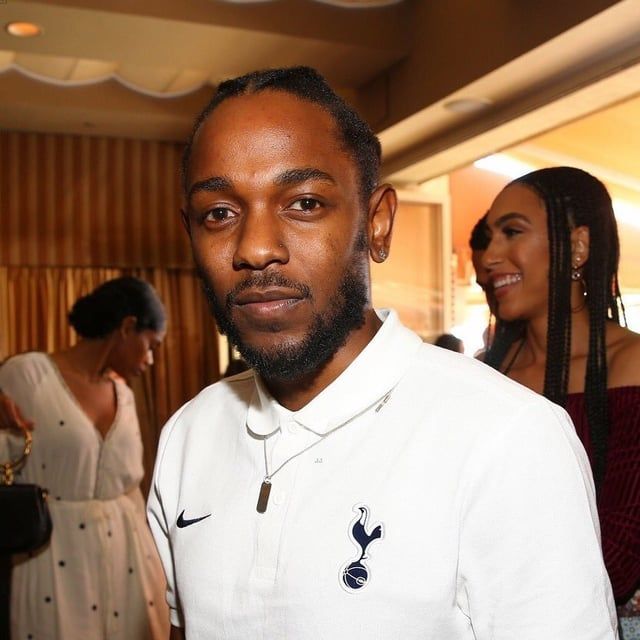 A 2017 photo of Kendrick Lamar wearing a white Nike polo with the Tottenham Hotspur crest.
